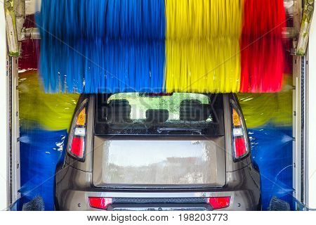 Car in automatic carwash between colorful brushes