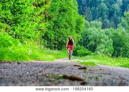 Man cycling in green forest on bike trial. Slimming activity
