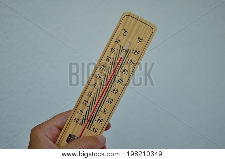 Mercury wooden thermometer shows very high temperature. Temperatures in Celsius and Fahrenheit degrees. Hot summer weather. Forty degrees over zero during the day.