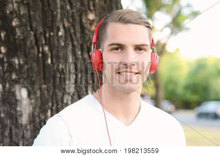 Close up of young handsome man with headphones in a park. Outdoors.