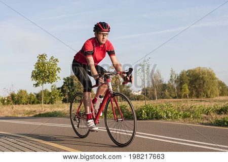 Sport and Cycling Concepts and Ideas. Male Caucasian Road Cyclist During Ride on Bike Outdoors. Completely Equipped in Professional Outfit.Horizontal Image