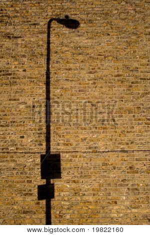 Lampen post skygge på en gul mur.
