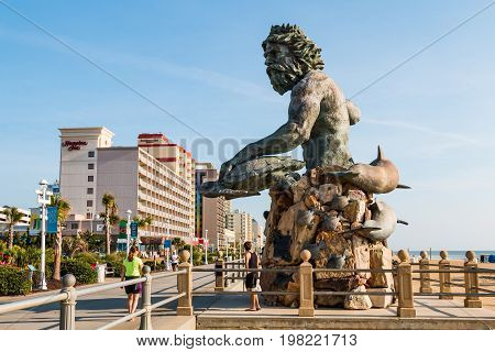 VIRGINIA BEACH, VIRGINIA - JULY 13, 2017:  The King Neptune statue by sculptor Paul DiPasquale along the oceanfront boardwalk lined with high-rise hotels at this popular tourist destination.