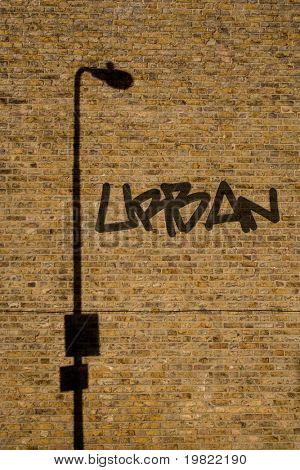 Urban graffiti og shadow stemmer fra en lygtepæl til en gul mur.