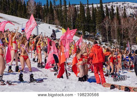 Group Of Young Happy Pretty Women On A Snowboard In Colorful Bikini With Flags.