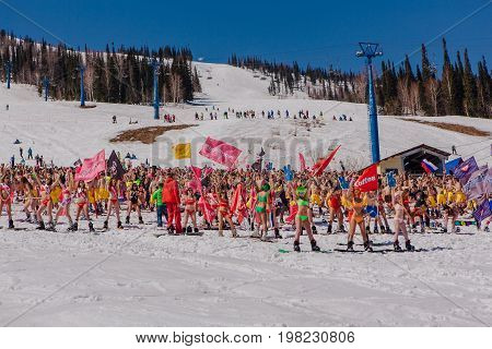 Group Of Young Happy Pretty Women On A Snowboard In Colorful Bikini With Flags.