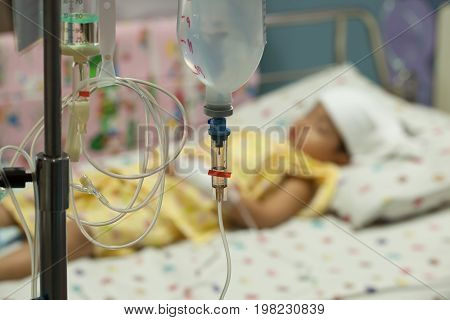 Close up saline IV drip for patient and Infusion pump in hospital In the hospital with a fragment of medical equipment and patients boy High fever for bacterial infections.