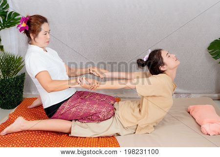 Asian woman getting traditional thai stretching massage by therapist