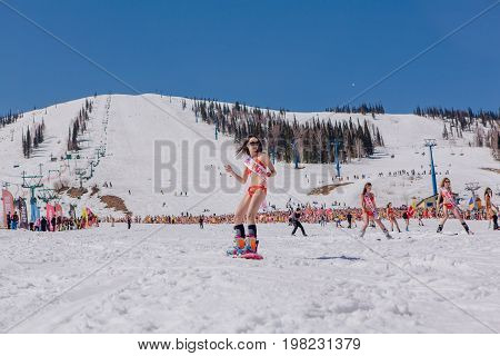 Sheregesh, Kemerovo region, Russia - April 22, 2017: Grelka Fest is a sports and entertainment activity for ski and snowboard riders in bikini. Group of young women on a snowboard in colorful bikini.