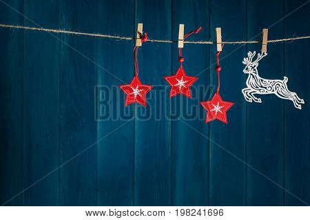 Christmas background. Reindeer and red christmas stars on clothespin on deep blue wooden background with copy space. Christmas or New Year card template.