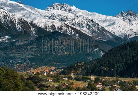 View of the Svanetian towers in Mestia village against mountains with glaciers snow peaks. Upper Svaneti Georgia. Georgian landmark