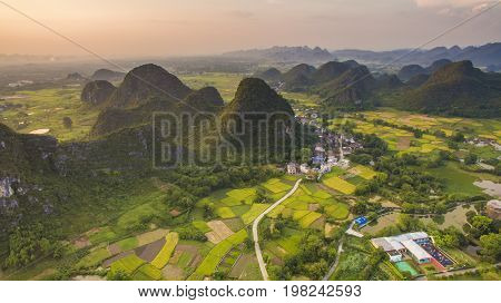 Aerial view of a village surrounded by Padi fields and hills in Guanxi China