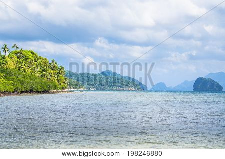 Coastline full of rocky islands covered with palm trees in El Nido, Philippines.