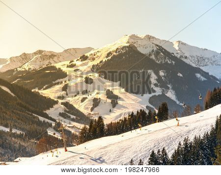Downhill slope in Saalbach Hinterglemm Leogang winter resort, Tirol, Austria, Europe. Sunny morning with clear sky and illuminated mountain massive on the background.