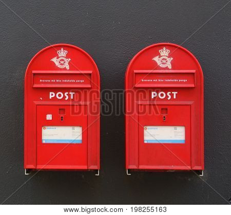 Falster. June-14-2017. Two danish red postbox on the black wall.
