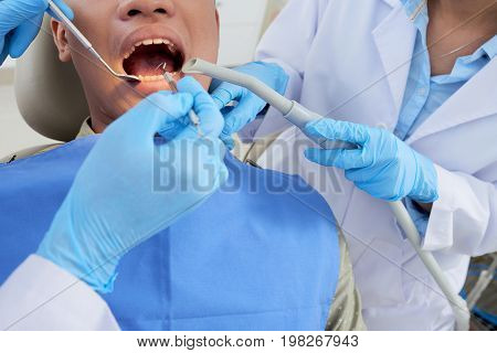 Asian young man opening his mouth widely when having teeth examination