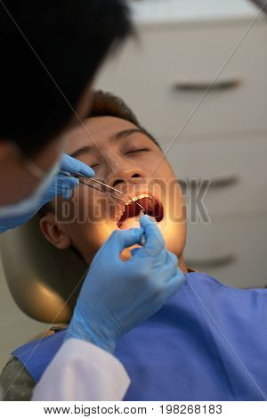Young man opening his mouth so the doctor can examine every tooth