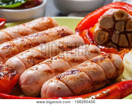 Close up view of chicken homemade sausages. Grilled sausages and grilled vegetables in green plate. Copy space.
