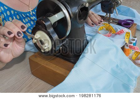 Woman hand on sewing machine.Dressmaker work on the sewing machine. Hobby sewing fabric as a small business concept. Female tailor threading leather material on sewing machine