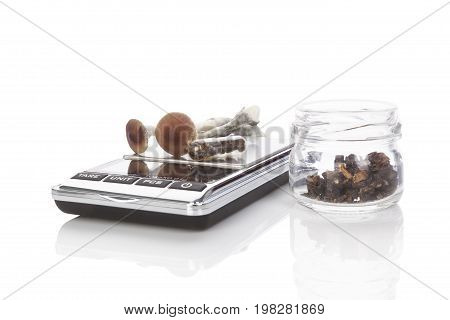 Fresh magic mushrooms gelcaps on digital scale dried mushrooms in glass jar isolated on white background.Alternative medicine.
