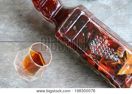 Local whiskey in a glass with bottle of herbal liquor in Thailand.
