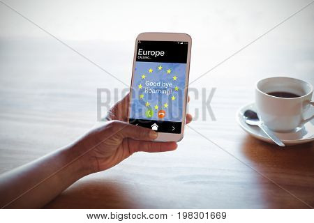 Good bye roaming text and European Union flag on mobile screen against cropped hand of woman using phone at table