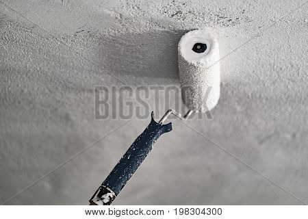 Roller With White Paint On A Concrete Ceiling