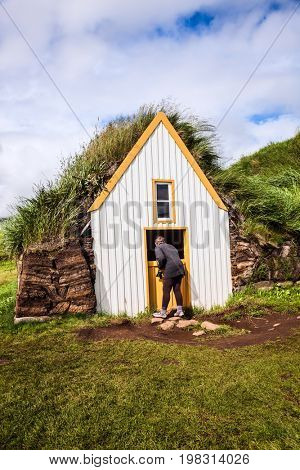 The elderly woman photographs the interior of the old house. Ethnographic Museum-estate Glaumbaer, Iceland. The concept of the historical and cultural tourism