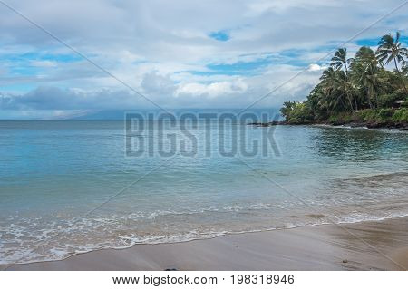 A lone fisherman tries his luck on a beach in the Kahana area of Maui Hawaii.