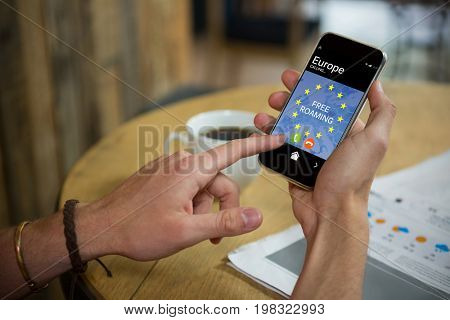 Free roaming text and European Union flag on mobile display against man using mobile phone at table in cafe