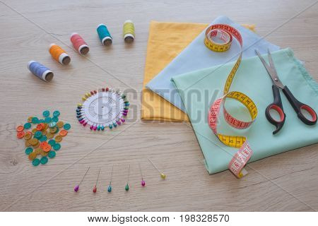 scissors and sewing kit includes threads of different colors thimble and other sewing accessories on wooden table. tools for sewing for hobby