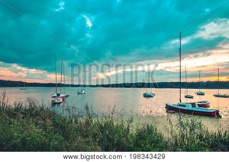 Summer evening landscape. Boats on the lake and colorful sky.