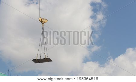 A crane lifting heavy equipments on a construction site - telephoto view in front of blue sky
