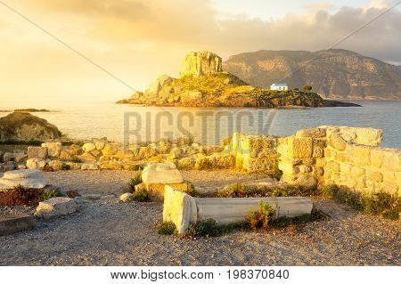 Ancient ruins and small island Kastri with traditional orthodox church in Kefalos bay in Kos island Greece.
