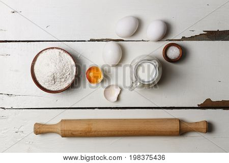 Baking background. Cooking ingredients for yeast dough and pastry, eggs, flour and milk on white rustic wood. Top view with copy space, mockup for menu, recipe or culinary classes. on the wooden table