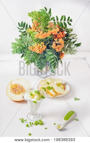 Dessert from melon cottage cheese and mint bouquet of mountain ash on a white background