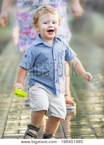 Playful happy funny little boy running away from his mother and laughing at summer day