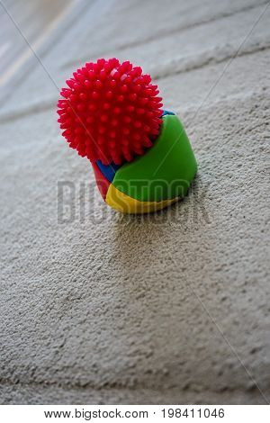 red massage ball with spikes with juggle ball on grey carpet