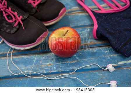 High angle view of womenswear with apple and headphones on wooden table