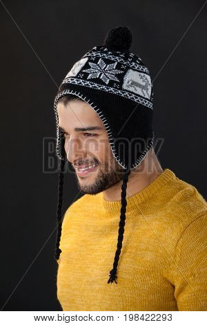 Thoughtful man in wooly hat against black background