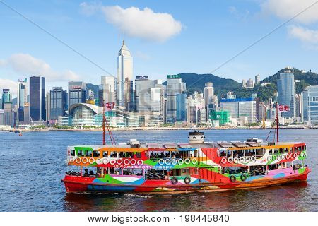 HONG KONG - JULY 10 2017: A colorful Star Ferry approaches a ferry terminal at Tsim Sha Tsui in Hong Kong. The city's iconic Star Ferry carries passengers across Victoria Harbour between Hong Kong Island and Kowloon since 1888.