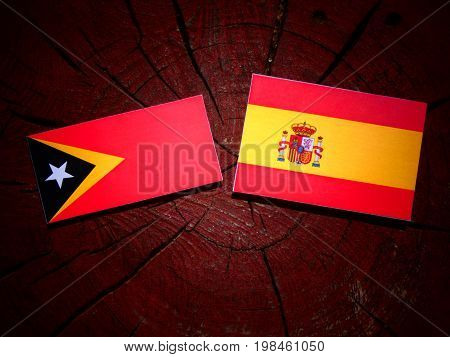 East Timorese Flag With Spanish Flag On A Tree Stump Isolated