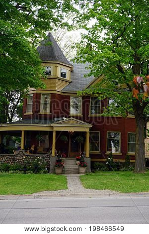 CADILLAC, MICHIGAN / UNITED STATES -  MAY 31, 2017: A red brick home with a wraparound porch and a turret in Cadillac's Courthouse Hill Historic District.