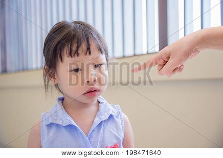 Little Asian girl feeling sad while parent scolding her at home