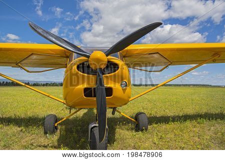 Light yellow airplane in grassy airfield. The propellers of aircraft close up
