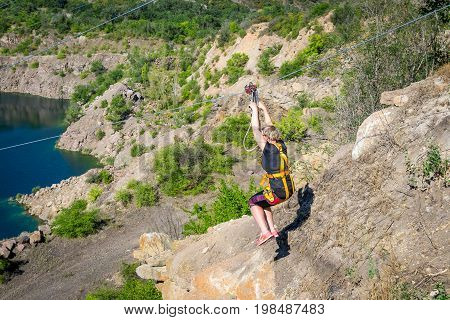 Ukraine Migea - July 30 2017: Zipline. The woman in the equipment slides on a steel cable. Trolley Track Over the lake. Extreme and active rest.
