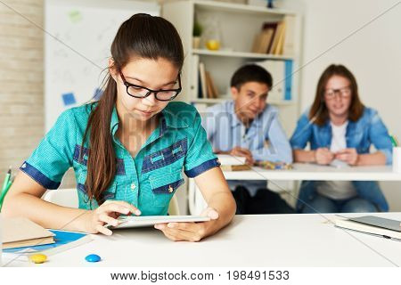 Portrait of teenage schoolgirl using digital tablet during lesson in class