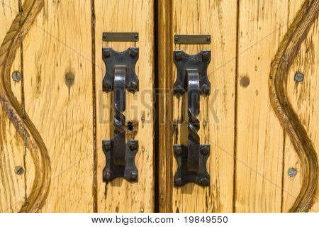 Iron door handles on the yellow wooden doors of a church building