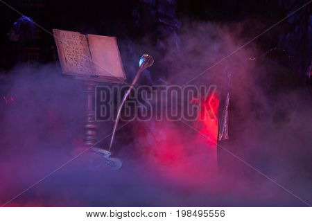 decoration, atmosphere, other world concept. decorating elements for perfomance in mist, grand bookrest, grimoire with some alchemical simbols and magical staff in form of cobra
