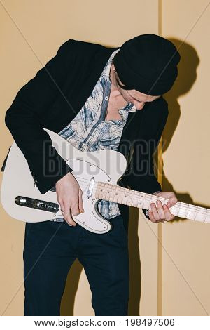Male guitarist assiduously playing guitar closeup. Music concert repetition, recording in studio
